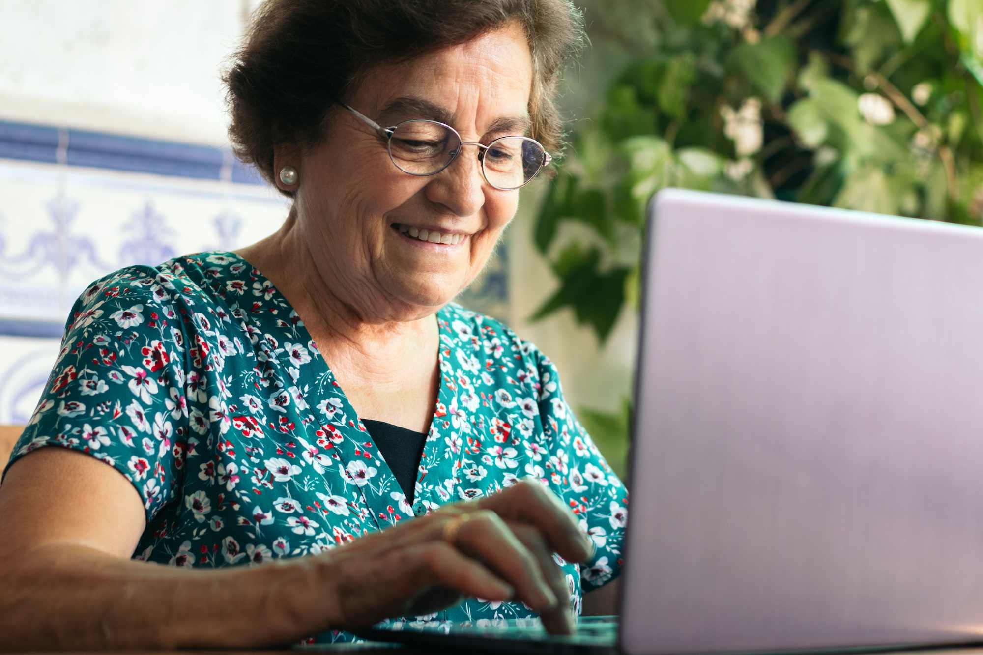 A senior woman wearing glasses using a laptop computer to learn about medicare